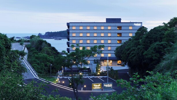 Ein mehrstöckiges Hotel mit modernem Design in der Nähe eines Gewässers und Blick auf die Küste.