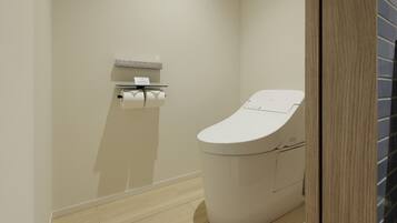 Ein modernes Badezimmer mit Toilette, Papierhandtuchspender und Holzboden.