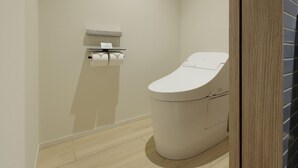 Ein modernes Badezimmer mit Toilette, Papierhandtuchspender und Holzboden.