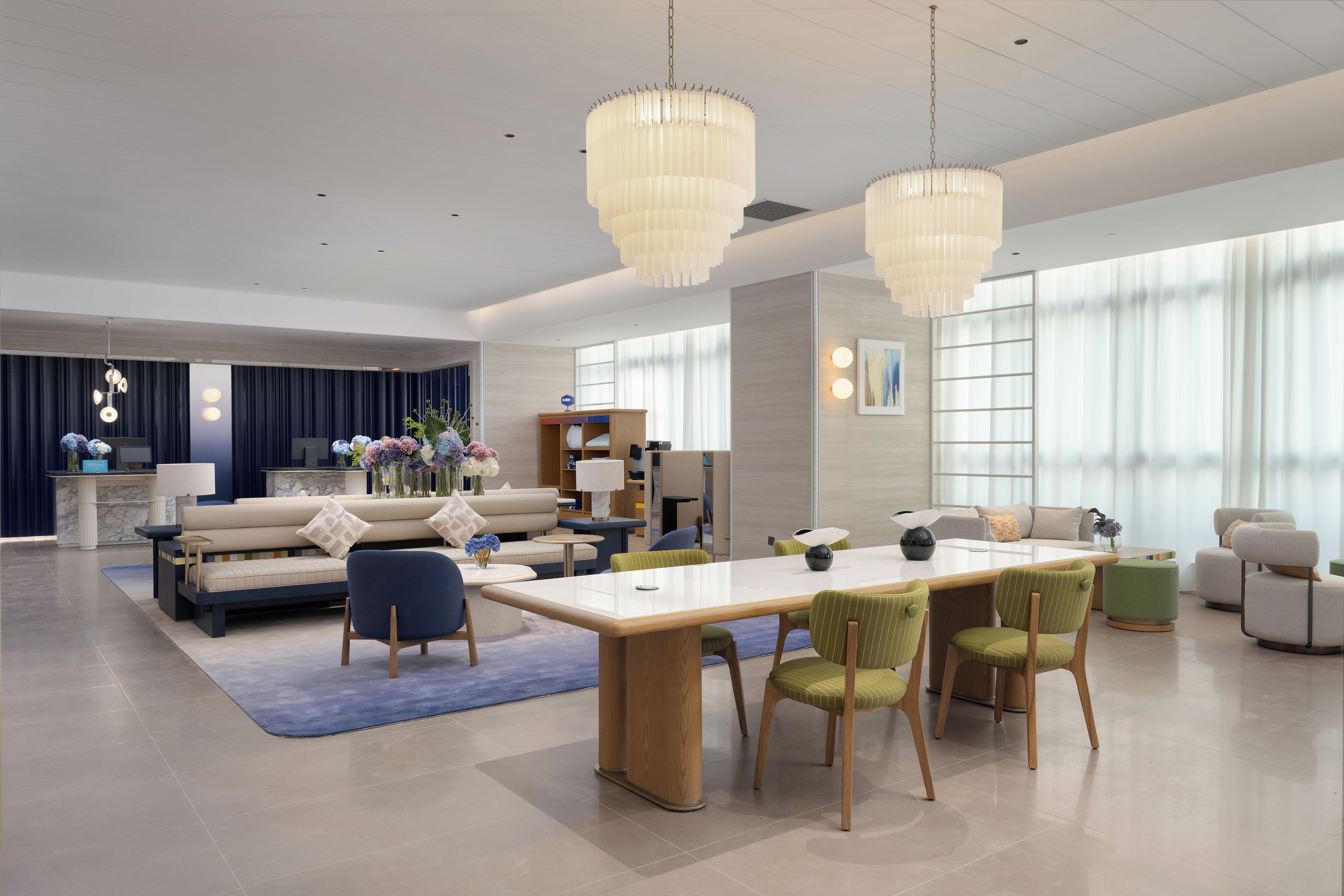 Een moderne hotellobby met een receptiebalie, een zithoek en een eetgedeelte.