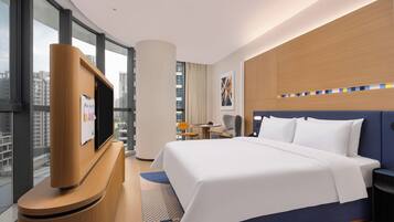 Une chambre d’hôtel avec un lit, une télévision, un bureau et une vue sur la ville.