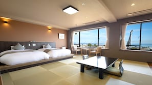 A hotel room with a large bed, a dining table, and a view of the city. - Beppu Onsen Choubounoyado Shiori (Beppu)