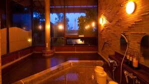 Ein Wellnessraum mit einer großen Badewanne, einer Holzwand und einem Fenster mit Blick auf eine Stadtlandschaft.