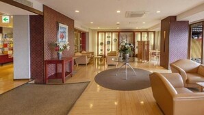 Eine Hotelhalle mit einer Rezeption, einer Sitzecke und einem Tisch mit Blumenvase.
