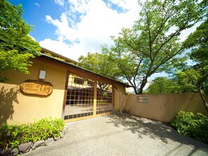A building with a traditional Japanese entrance, a wooden sign with Japanese characters, and a stone pathway leading to the entrance. - Beppu Onsen Choubounoyado Shiori (Beppu)