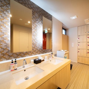 Une salle de bain d’hôtel avec deux lavabos, un grand miroir et un espace pour les casiers.