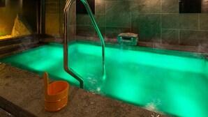 A spa area with a green-lit hot tub, a metal ladder, and a small wooden stool. - Super Hotel Tokyo Shiba (Tokyo)