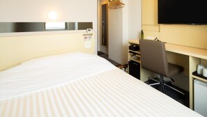 A hotel room with a bed, desk, chair, TV, and air conditioning unit. - Super Hotel Tokyo Shiba (Tokyo)