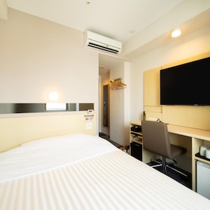 Une chambre d’hôtel équipée d’un lit, d’un bureau, d’une chaise, d’une télévision et d’un appareil de climatisation.