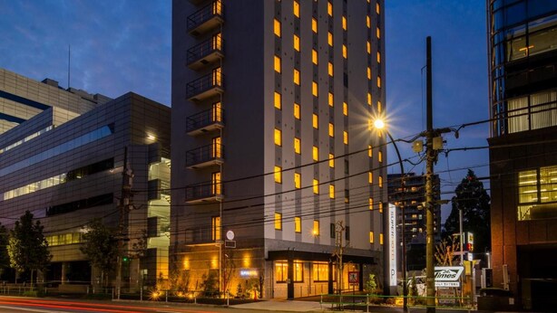 A Super Hotel with multiple floors, illuminated windows, and a prominent sign at the top. - Super Hotel Tokyo Shiba (Tokyo)