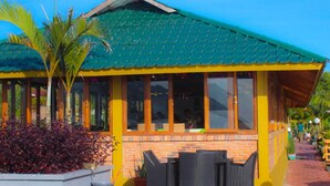 A building with a green roof, large windows, and outdoor seating. - Toba Village Inn (Samosir)