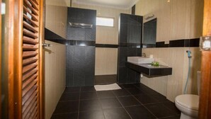 A modern bathroom with a shower, toilet, and sink. - Toba Village Inn (Samosir)