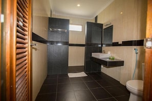 Een moderne badkamer met douche, toilet en wastafel.