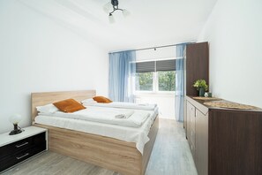 A bedroom with a bed, bedside table, lamp, and a view of the outdoors. - RentPlanet - Apartament Górczewska (Warszawa)