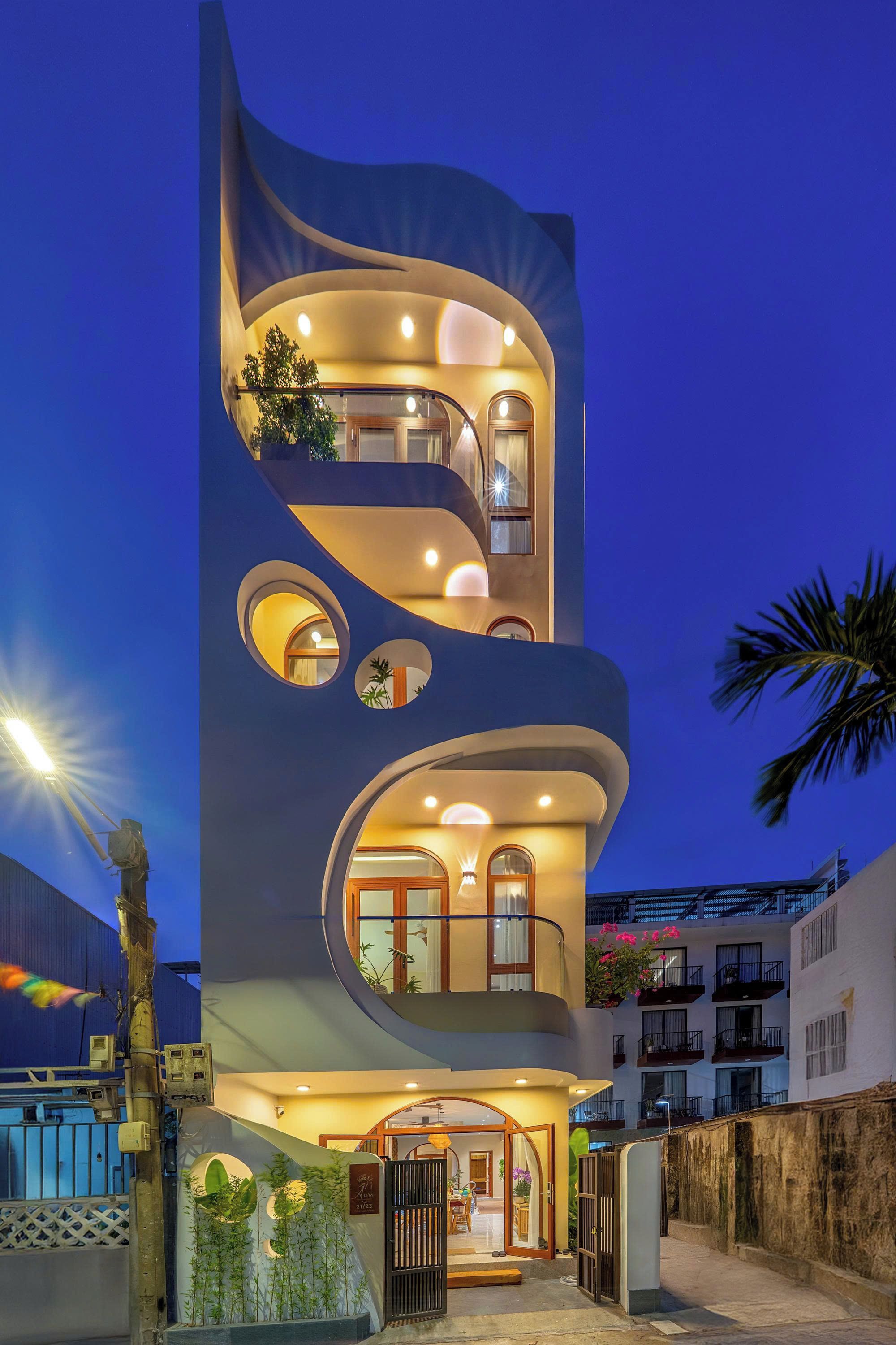 A modern multi-story building with a unique curved facade, multiple balconies, and a well-lit entrance.