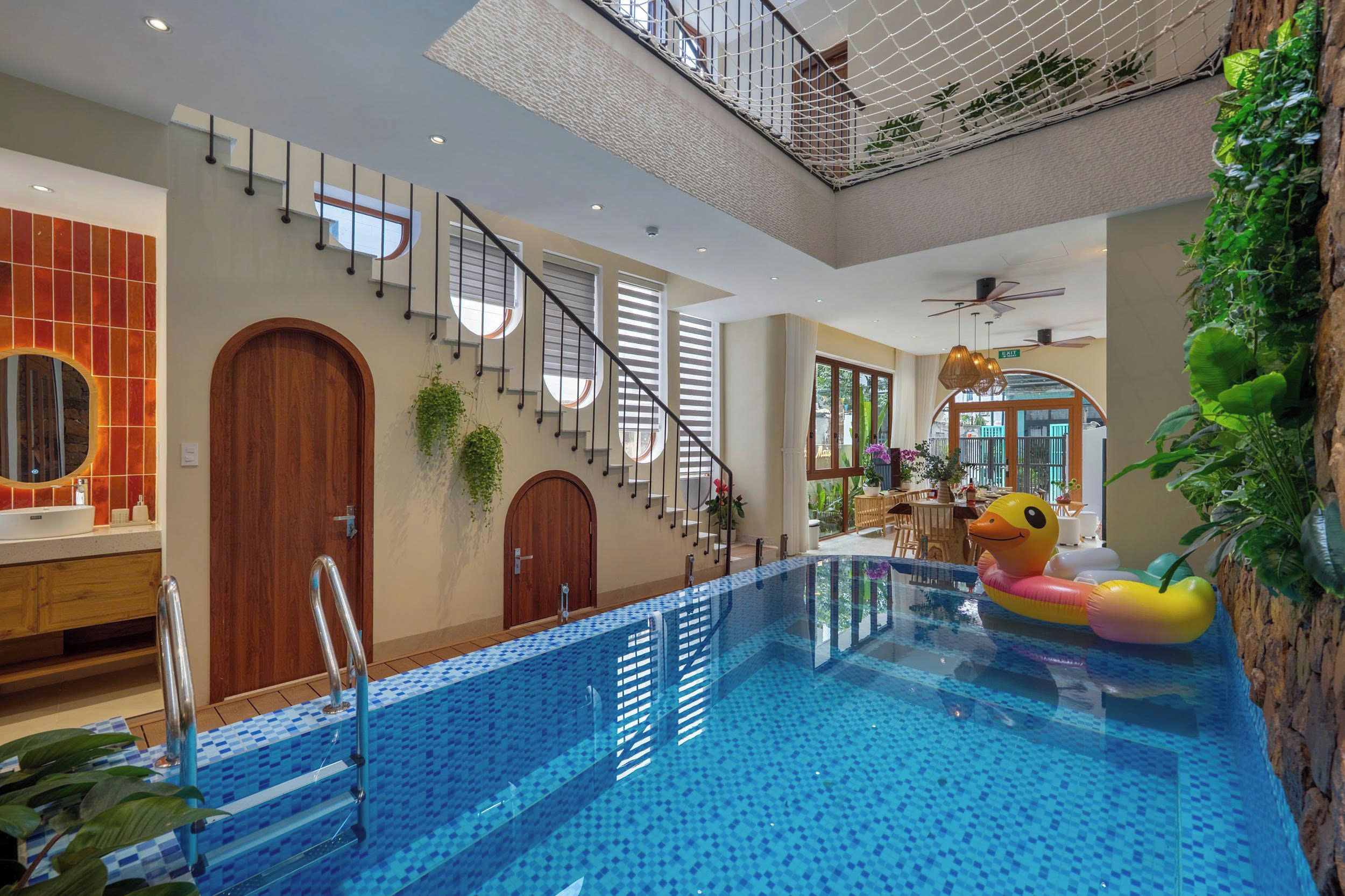 An indoor swimming pool with a duck float, a staircase with a railing, and a view of the outdoors.