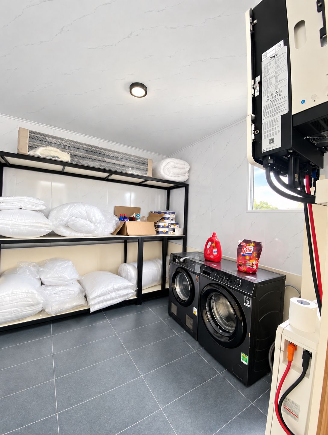 A laundry room with a washing machine, shelves with folded towels, and a power outlet.