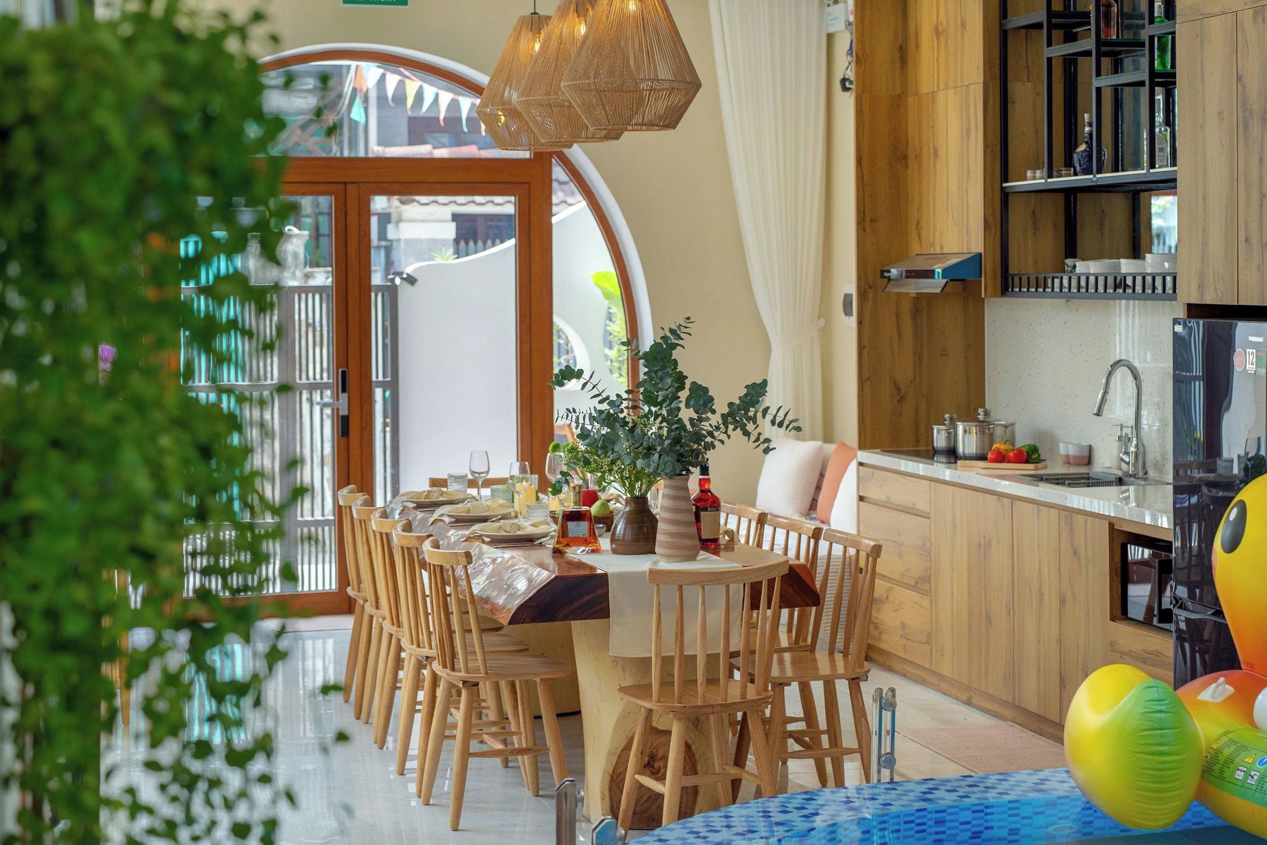 A modern kitchen with wooden cabinets, a built-in oven, and a dining area with a round table and chairs.