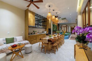 Ein modernes Wohnzimmer mit Essbereich, Holzmöbeln und einer Küche mit integriertem Regal.