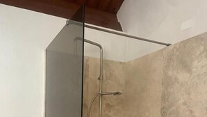 A glass-enclosed shower with a metal frame, beige tiled walls, and a wooden ceiling. - Agriturismo Cavendo Tutus (Roma)