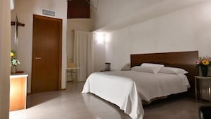 A bedroom with a large bed, a wooden headboard, a bedside table with a lamp, and a door with a curtain. - Agriturismo Cavendo Tutus (Roma)