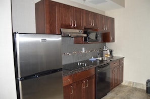 Cozinha com eletrodomésticos de aço inoxidável, armários de madeira e painel de azulejos.