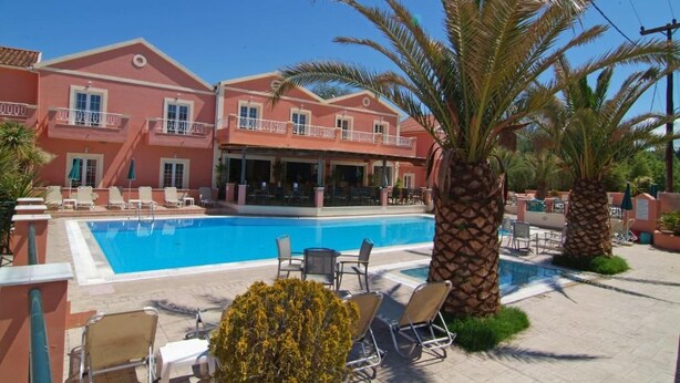 Zona junto a la piscina con sillones de descanso, piscina y un edificio con balcones.