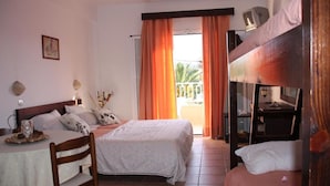 Habitación de hotel con cama, escritorio, silla, literas y balcón con cortinas.
