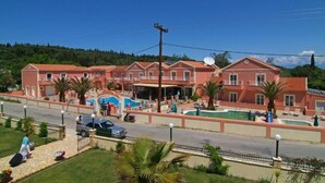 Un hotel con varios edificios de techo rojo, una piscina y vista a la calle.