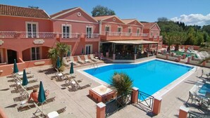Un hotel con piscina, sillas de descanso y sombrillas.