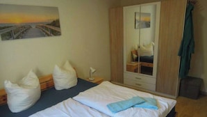 Una camera da letto con due letti, un armadio, un comodino e un quadro appeso al muro.