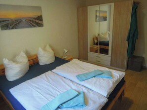 A bedroom with two beds, a wardrobe, a bedside table, and a painting on the wall. - B 1 Directly at Lake Netzen (Kloster Lehnin)