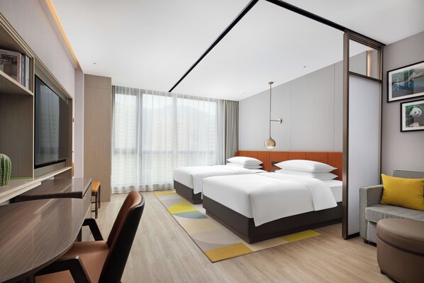 A hotel room with a bed, a desk, a chair, a TV, and a window with curtains.