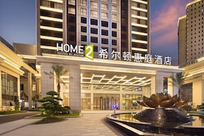 A hotel with a modern facade, a prominent entrance, and a decorative water feature in front.