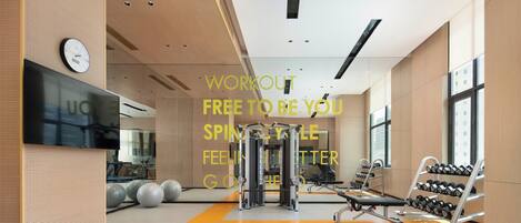 Een moderne sportschool met trainingsapparatuur, een klok en een groot raam.