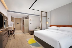 A hotel room with a bed, a desk, a chair, a television, and a wardrobe.