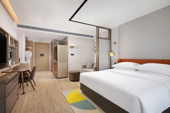 A hotel room with a bed, a desk, a chair, a television, and a wardrobe.