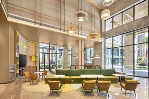 A spacious lobby with a green sofa, yellow chairs, and a TV on the left. - Home2 Suites BY Hilton Xingwen Yibin (Yibin)