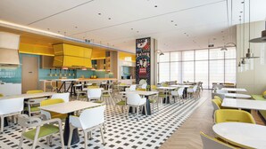Un restaurante moderno con barra central, varias mesas y sillas para comer.