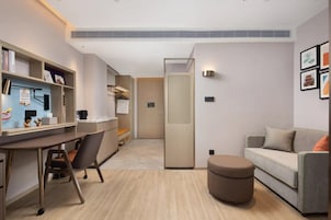 Una habitación moderna y bien iluminada con escritorio, silla y sofá.