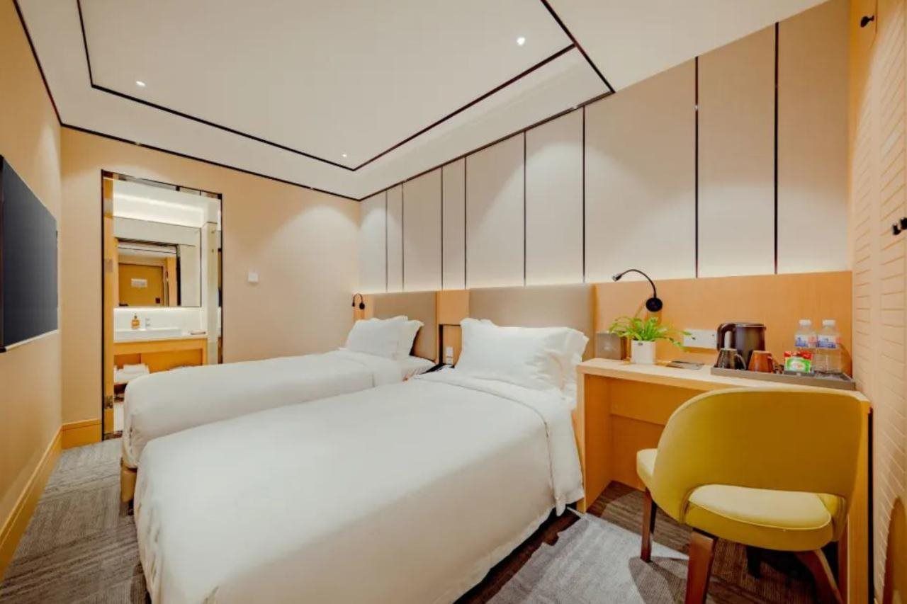 A hotel room with two beds, a desk, a chair, and a television.
