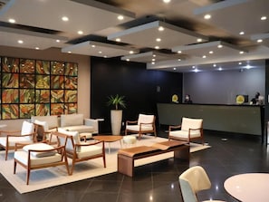 Un moderno vestíbulo con arreglos de asientos, un mostrador de recepción y un amplio elemento decorativo en la pared.