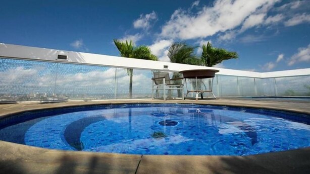 Una piscina con cielo azul despejado y palmeras al fondo.