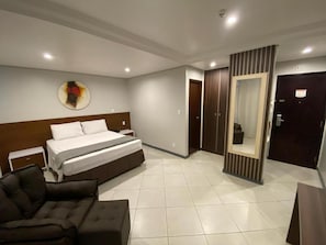 Una habitación de hotel con cama, sofá, espejo y puerta.