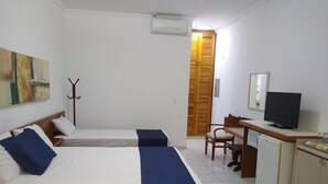 Una camera d'albergo con due letti, una scrivania, una televisione e un armadio.