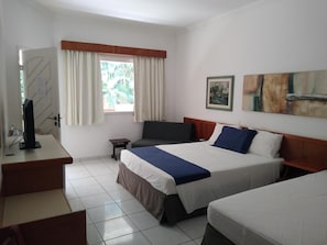 A hotel room with a bed, a desk, a chair, a TV, and a window with curtains. - Riviera Service- Hotel Suites 209 e 308 (Bertioga)