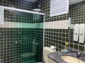 A bathroom with a glass-enclosed shower, a toilet, and a sink with a marble countertop. - Riviera Service- Hotel Suites 209 e 308 (Bertioga)