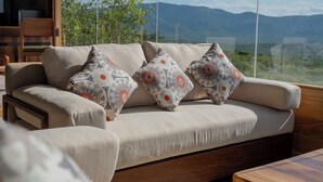 A sofa with patterned cushions and a view of mountains through a large window.