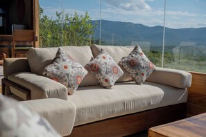 A sofa with patterned cushions and a view of mountains through a large window.