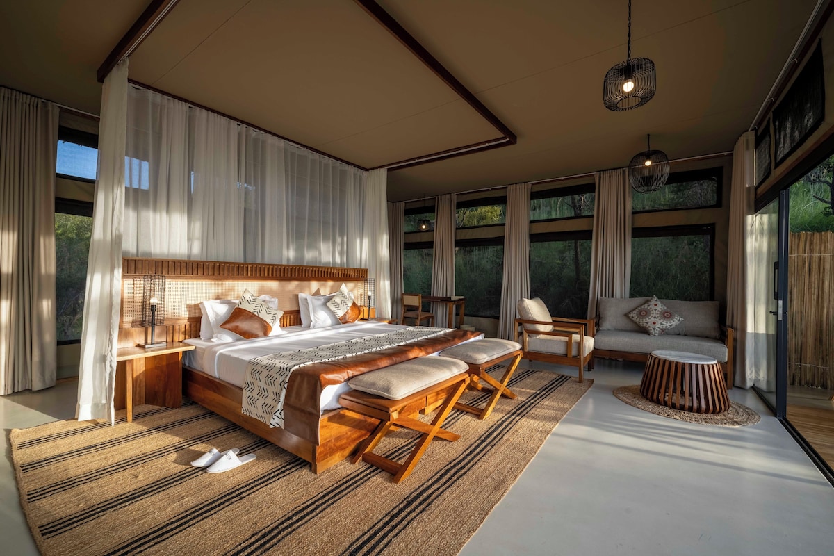 Quarto moderno com cama grande, área de estar e vista para o exterior.
